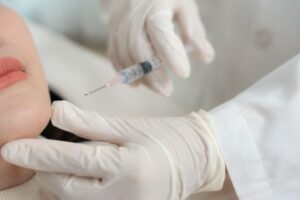 A doctor using a syringe to perform an aesthetics clinic polynucleotides treatment on a patient