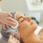 a female hearing hair protection, receiving a skin booster injection from an aesthetic clinic beautician