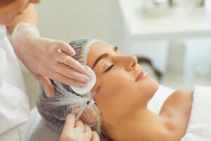 a female hearing hair protection, receiving a skin booster injection from an aesthetic clinic beautician