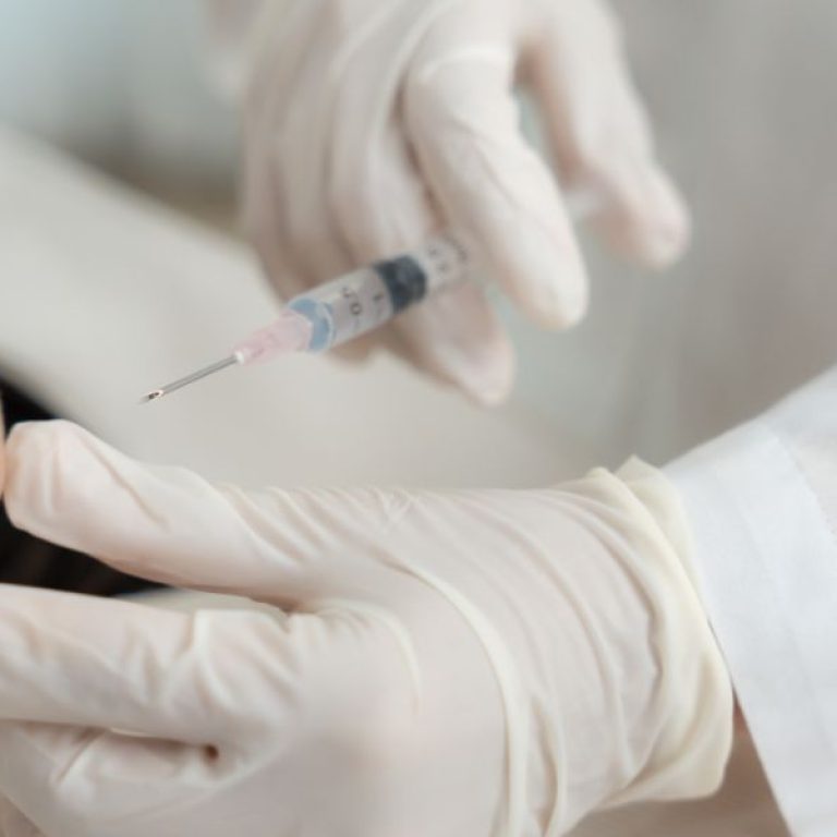 A doctor using a syringe to perform an aesthetics clinic polynucleotides treatment on a patient