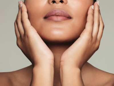a mixed race woman holding her face. her skin is clear from skin treatments